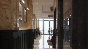 A spacious, well-lit hallway with marble flooring and walls, leading to a seating area with a large window. - Splendid Secret Hotel (Hanoi)