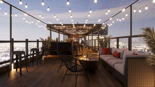 A rooftop lounge with a view of the city, featuring a wooden floor, seating area with a sofa and chairs, and string lights. - Splendid Secret Hotel (Hanoi)