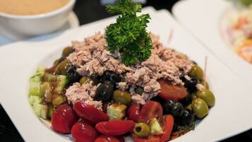 Ensalada de atún con aceitunas, tomates y adorno de perejil.