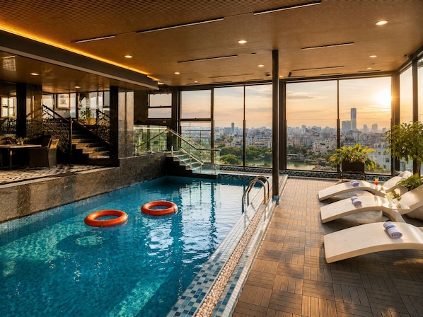 Una piscina interior con vistas despejadas de un paisaje urbano a través de amplias ventanas.