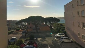 A residential area with parked cars, a large tree, and a building with multiple windows. - Whole apartment in Six-Fours-les-Plages, France (Six-Fours-les-Plages)