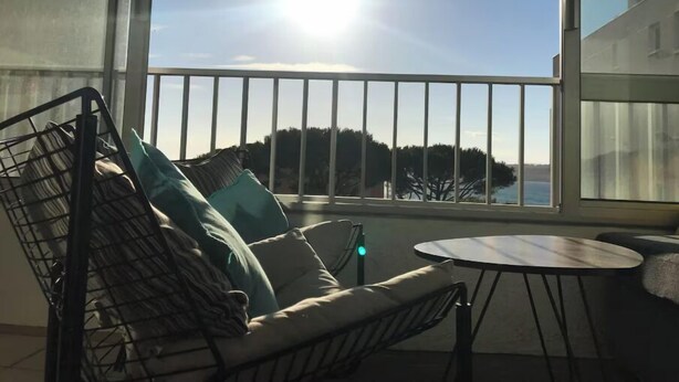 A balcony with a sofa and a small table, overlooking a scenic view. - Whole apartment in Six-Fours-les-Plages, France (Six-Fours-les-Plages)