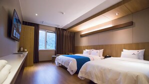 A hotel room with two beds, a TV mounted on the wall, a window with curtains, and a wooden headboard. - Amor Hotel (Changwon)