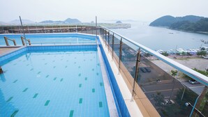 A rooftop pool with a clear view of the sea and distant mountains. - Amor Hotel (Changwon)