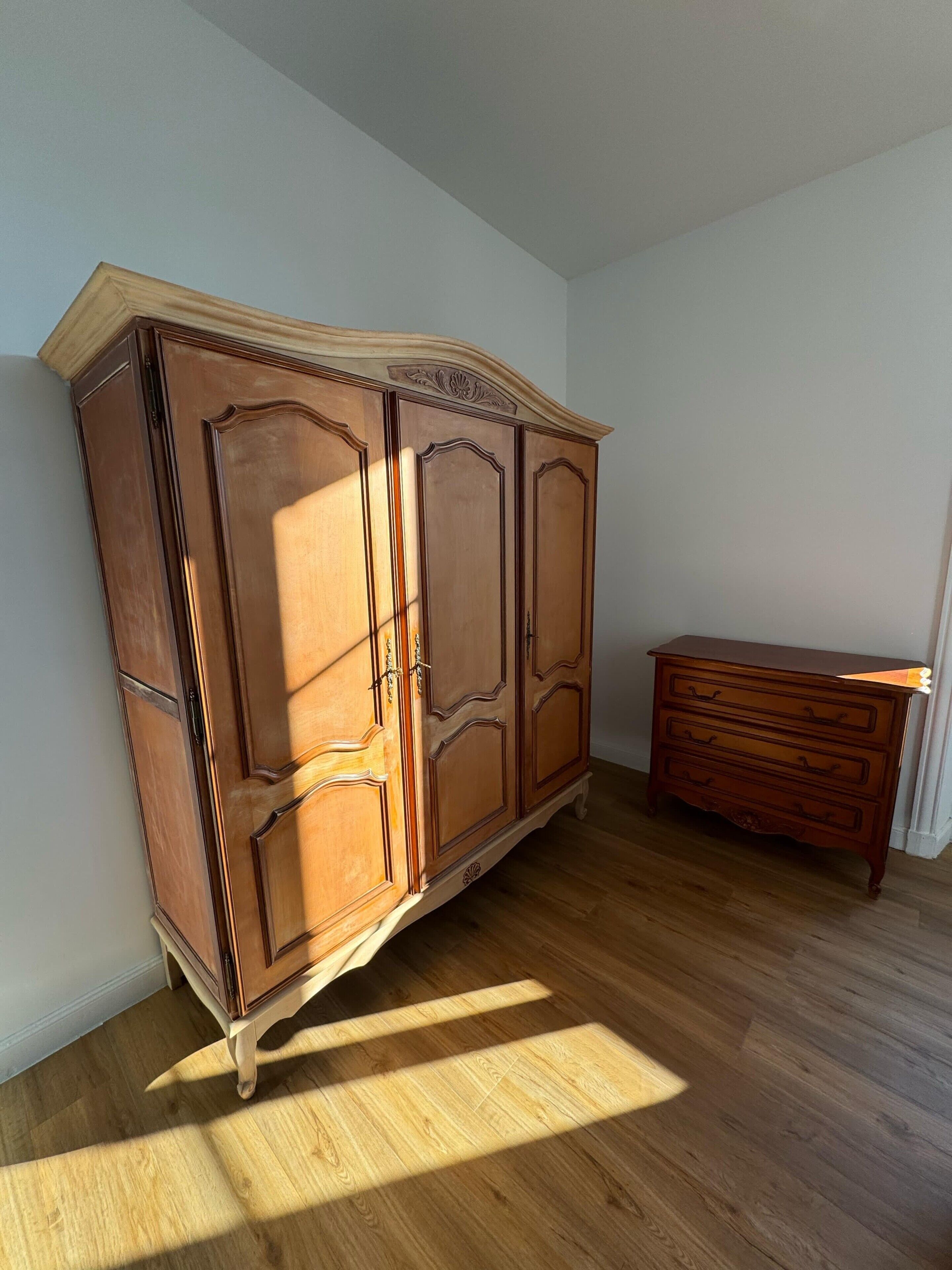 Un aparador de madera con parte superior curva y un pequeño baúl de cajones al lado derecho.
