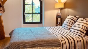 A bedroom with a large bed, a window, and a lamp. - House 1880 (Annonay)