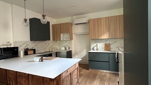 A modern kitchen with wooden cabinets, a marble backsplash, and a central island. - House 1880 (Annonay)