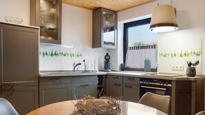 A modern kitchen with a dining table, cabinets, and a window.
