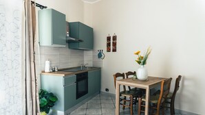 Eine kompakte Küche mit türkisfarbenen Schränken, einem Holztisch und einem Blumentopf.