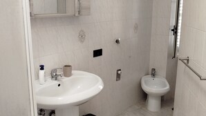 Ein Badezimmer mit einem weißen Waschbecken, einem Bidet und einem Spiegel über dem Waschbecken.