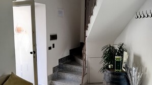 Eine Treppe mit Holzwurf, ein beiges Sofa mit Kissen, ein Blumentopf und eine Zierfaß.