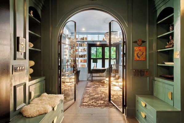 A library with bookshelves, a chandelier, and a bench.
