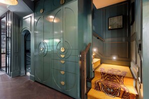 A modern interior with teal cabinetry, a wooden staircase, and a patterned cushion on the steps.