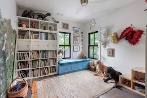 A cozy room with a bookshelf, a blue bed, and a leopard plush toy. - Abode Sauvage (Atlanta)