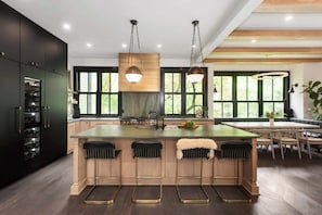 A modern kitchen with a central island, bar stools, and large windows. - Abode Sauvage (Atlanta)
