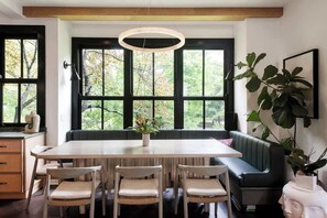 A dining area with a large table, four chairs, a bench, and a potted plant.