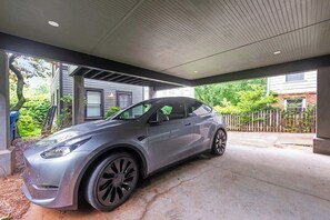Ein modernes Auto steht in einer überdachten Garage mit Betonboden und Metallträgern.