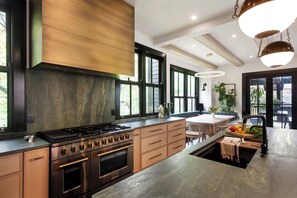 Una cocina moderna con un horno grande, armarios de madera y un comedor con mesa y sillas.