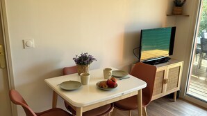 Un comedor con una mesa, sillas, un televisor y obras de arte en la pared.
