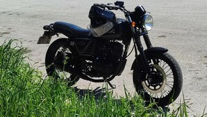 Une moto est garée sur une surface pavée, avec de l’herbe au premier plan.