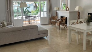 A spacious living room with a sofa, dining table, and chairs, large windows with curtains, and a fireplace. - Penthouse El Presidente Estepona 400 meters beach (Estepona)