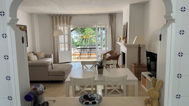 A living room with a sofa, dining table, chairs, a TV, and a balcony with outdoor furniture. - Penthouse El Presidente Estepona 400 meters beach (Estepona)