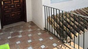 A building with a white exterior, a wooden door with a geometric pattern, and a tiled patio area. - Penthouse El Presidente Estepona 400 meters beach (Estepona)