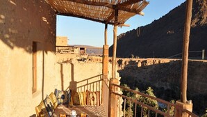 Un balcon en bois, agrémenté d’une table et de chaises, qui offre une vue sur un paysage montagneux.