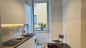 Eine kompakte Küche mit Essbereich, einer Waschmaschine, einem Spülbecken und einem Fenster mit Ausblick.
