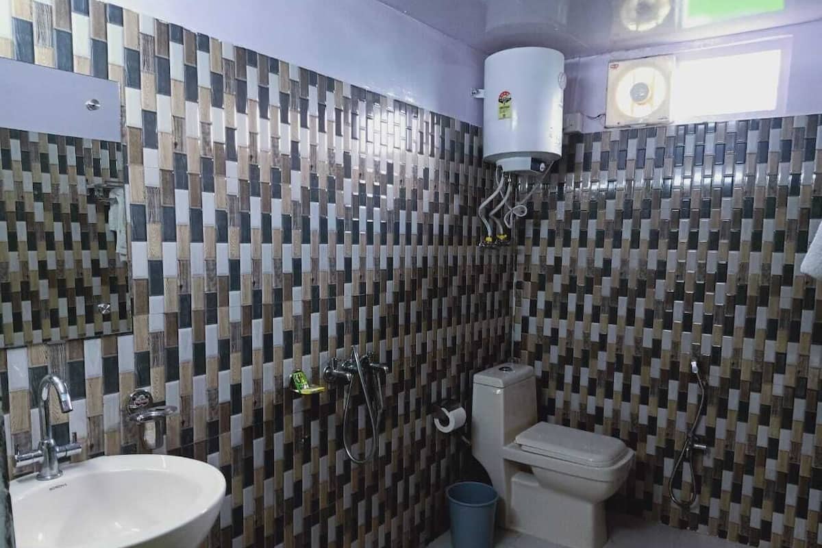 Une salle de bain avec un mur recouvert de carreaux, un lavabo, des toilettes et une douche.