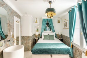 A bedroom with a bed, a vanity, a bathtub, and a chandelier. - Merveil Luxury Suites - Marais - Antoine I-II (Paris)