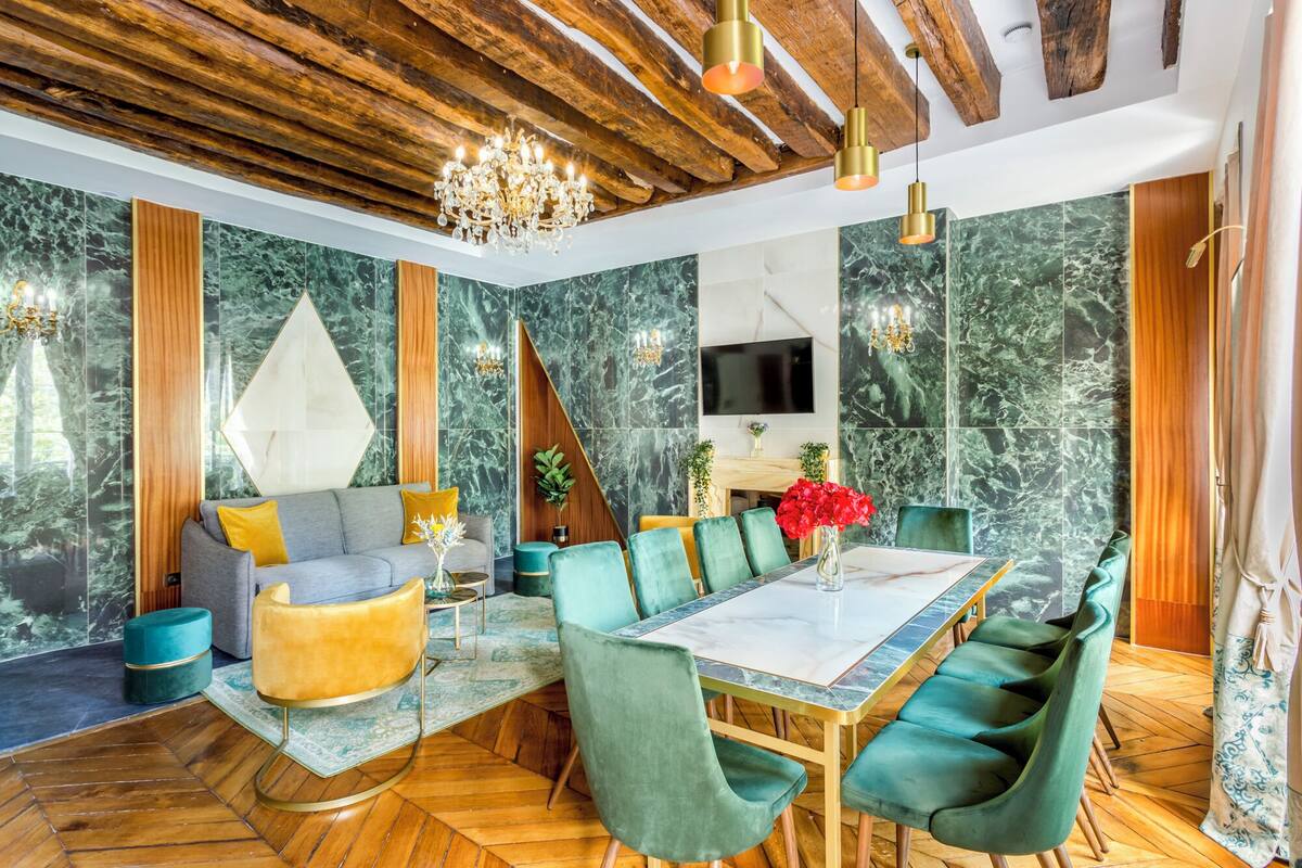 A modern dining area with a marble wall, wooden ceiling, and a chandelier.