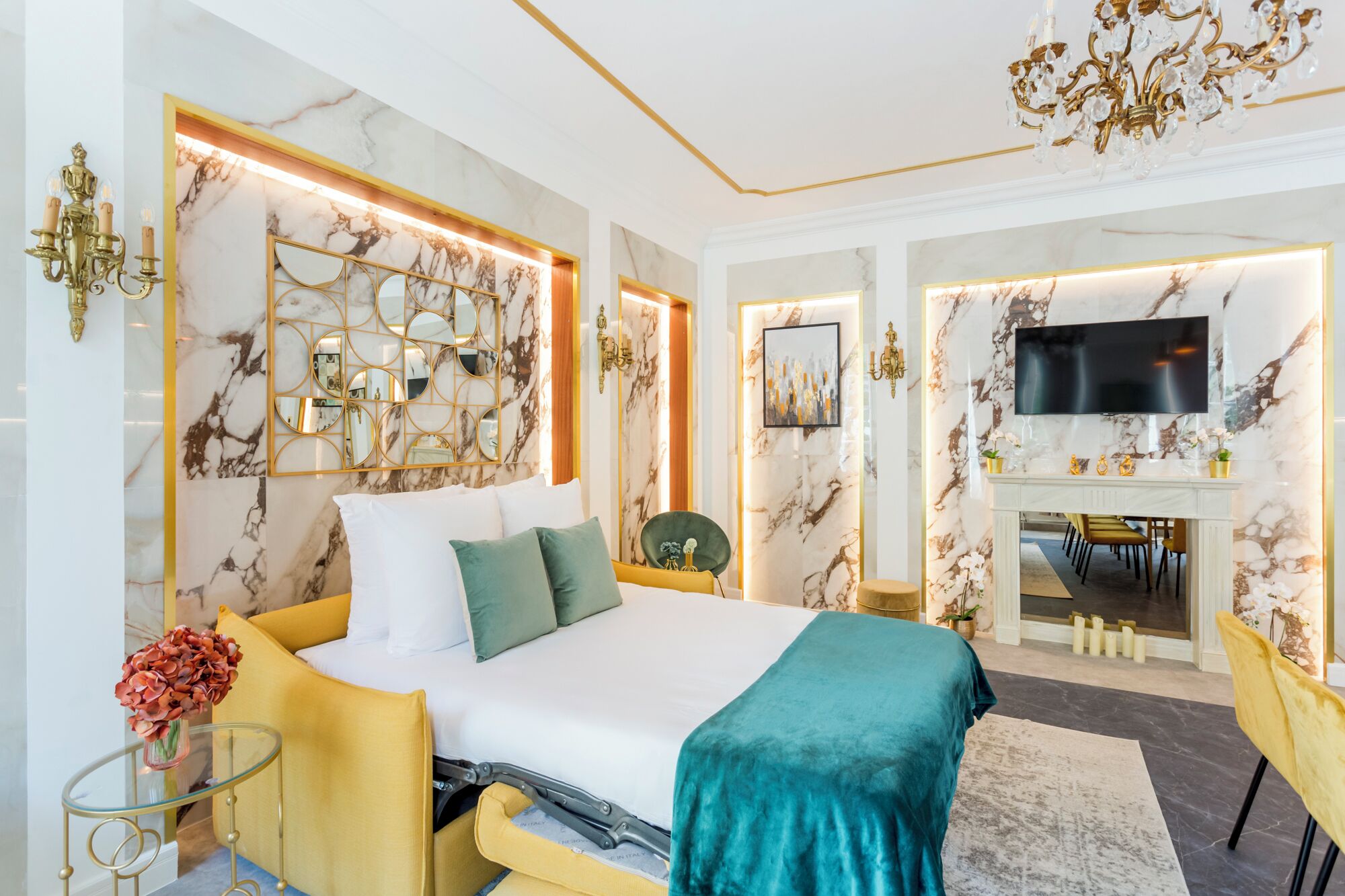 A modern bedroom with a bed, bedside tables, a TV, and a fireplace.