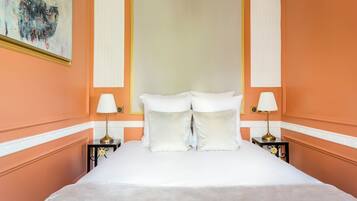 A hotel room with a large bed, white bedding, two bedside tables with lamps, and a painting on the wall.