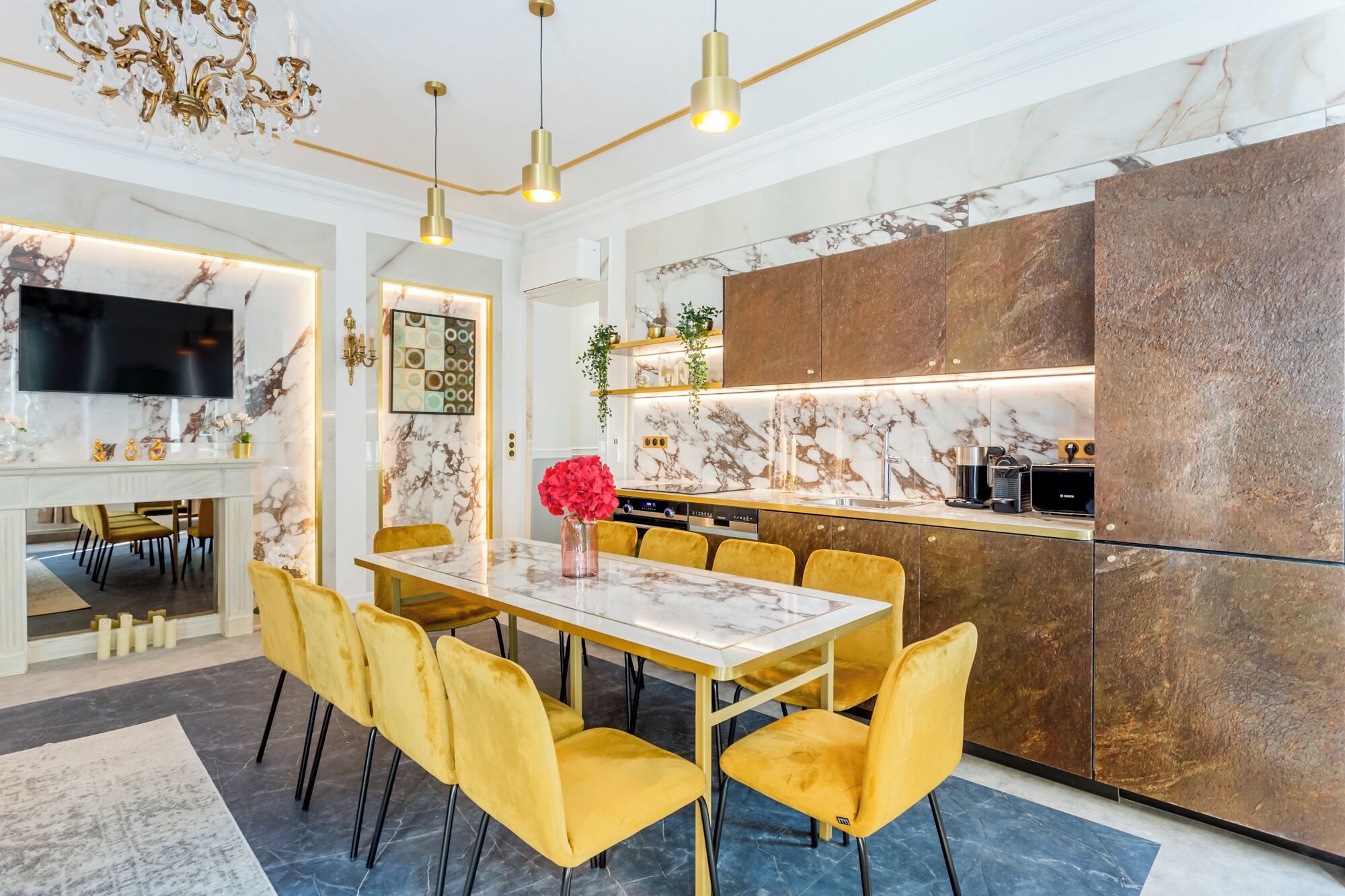 A modern kitchen with a marble countertop, a built-in oven, and a stainless steel refrigerator.
