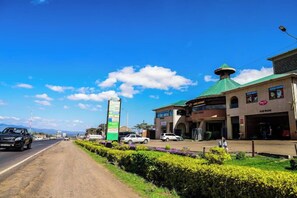 A roadside view with a signpost, a building with a green roof, and a road with vehicles. - Sanel Hotel and Lounge Naivasha (Naivasha)