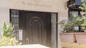 La entrada a Washingtonia Court, con una puerta de madera oscura, un cartel con el nombre y plantas en macetas al frente.