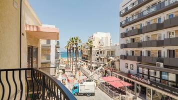 A balcony with a view of a beach, palm trees, and a restaurant named "Sofía Kebab".