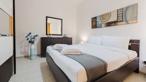 Una habitación de hotel moderna con una cama grande, un tocador, un espejo y un cuadro en la pared.