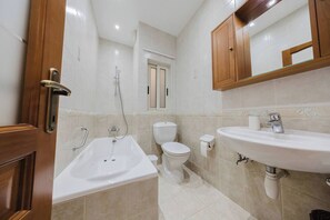 A bathroom with a bathtub, toilet, and sink. - Spacious seafront apartment in Għadira Bay with 3 bedrooms, 2 bathrooms, and a large terrace boasting spectacular sea views. Located on the third floor (no lift) and only 1 minute from the sandy beach — perfect for up to 5 guests. (Il-Mellieħa)
