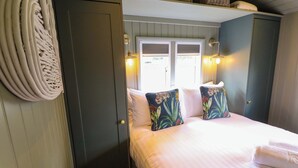 A bedroom with a bed, pillows, a door, and a window. - Bluebell (Grimsby)