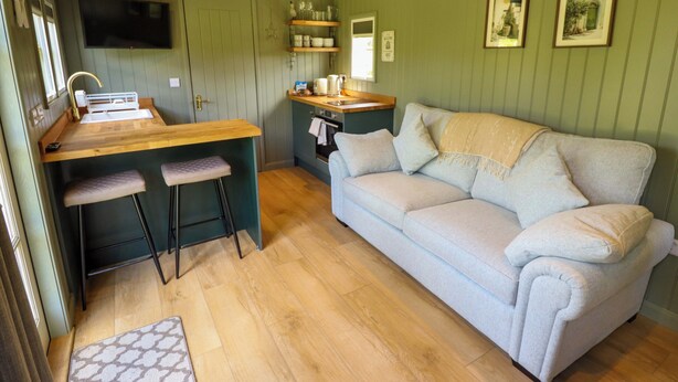 A compact living space with a kitchenette, a sofa, and a small bar area. - Bluebell (Grimsby)
