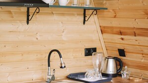 Une cuisine avec des murs en bois, un évier en acier inoxydable, une machine à café et un égouttoir à vaisselle.