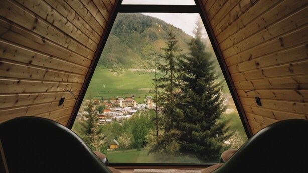 Une pièce dotée d’une grande fenêtre donnant sur une ville et des montagnes.