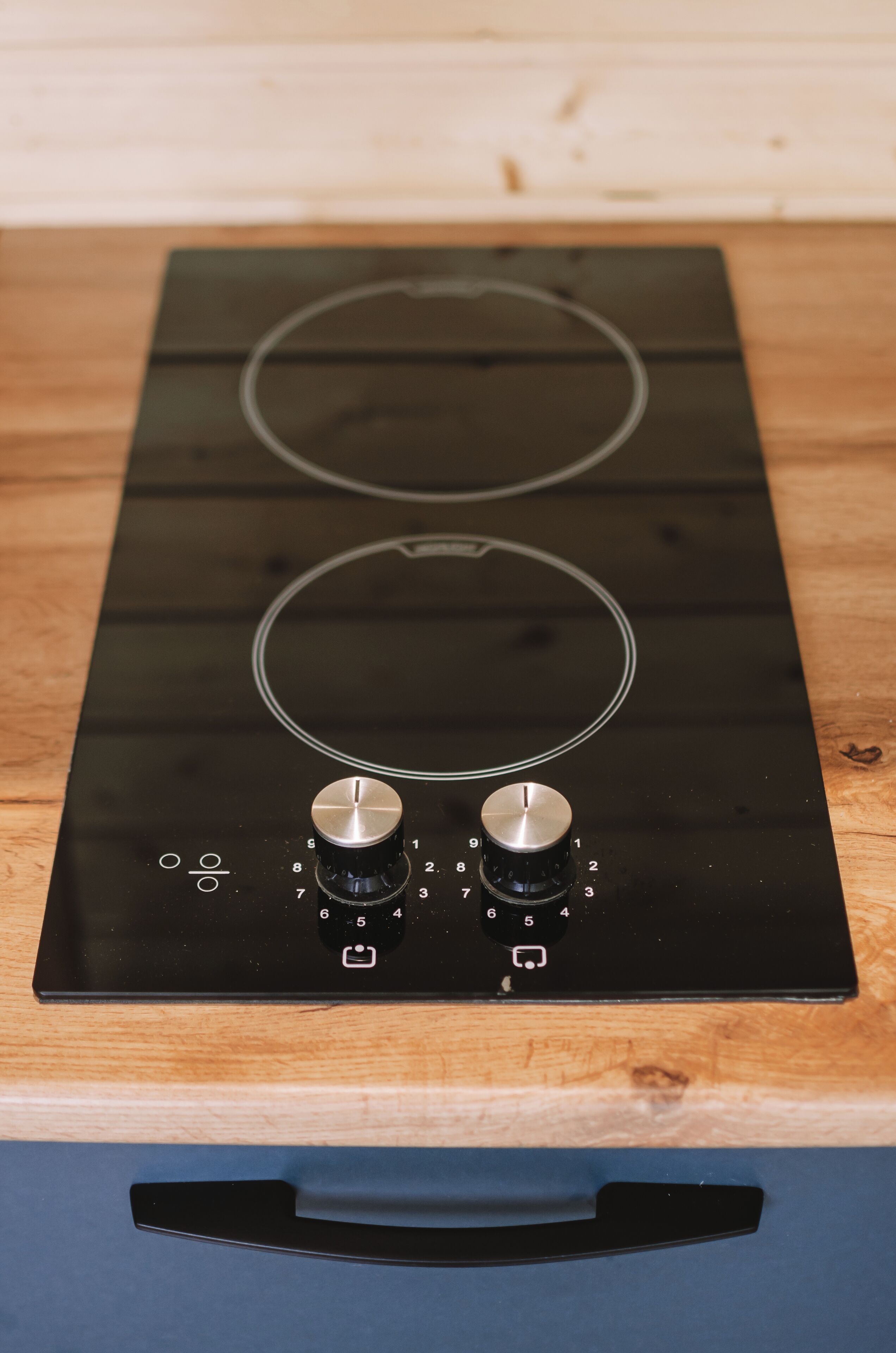 A black induction cooktop with two knobs and a control panel.