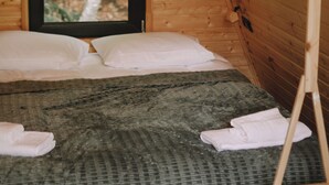 Une chambre dans un chalet en bois, avec un lit, des oreillers et une fenêtre.