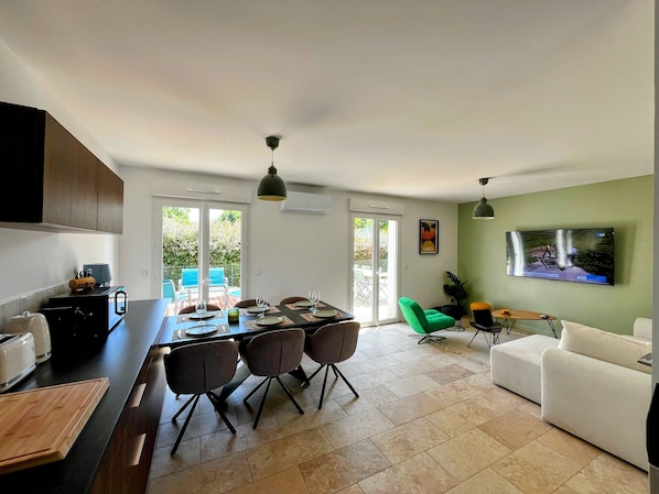 Una cocina moderna con comedor, televisor montado en la pared y vistas al exterior.