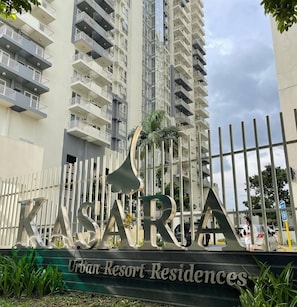 A sign for 'KISARA Urban Resort Residences' with a modern building in the background.