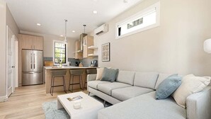 A modern kitchen with a built-in oven, a dining area with a white table and chairs, and a grey sofa with cushions. - Hamilton Place - 305 (3 units) Sleeps 12 (Traverse City)