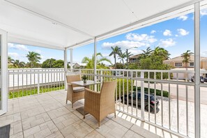 Un balcón con muebles de mimbre y vista a una zona residencial.
